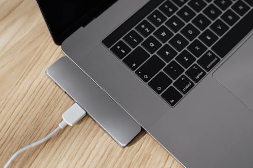 Free From above of gray colored contemporary netbook with usb port multiplier and white cable connected to usb hub on wooden table Stock Photo