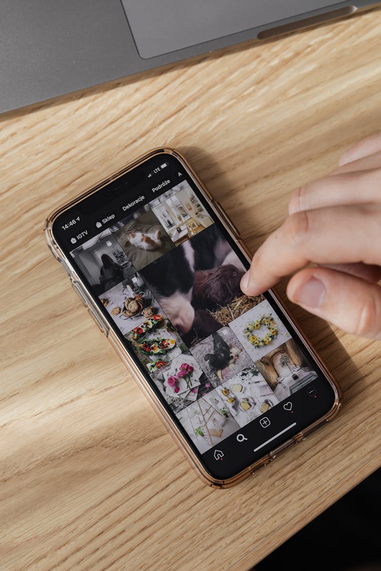 Crop Person Browsing Smartphone On Wooden Table