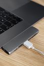 From above closeup of modern stylish thin netbook with smart usb hub equipment and connected white cable placed on wooden surface