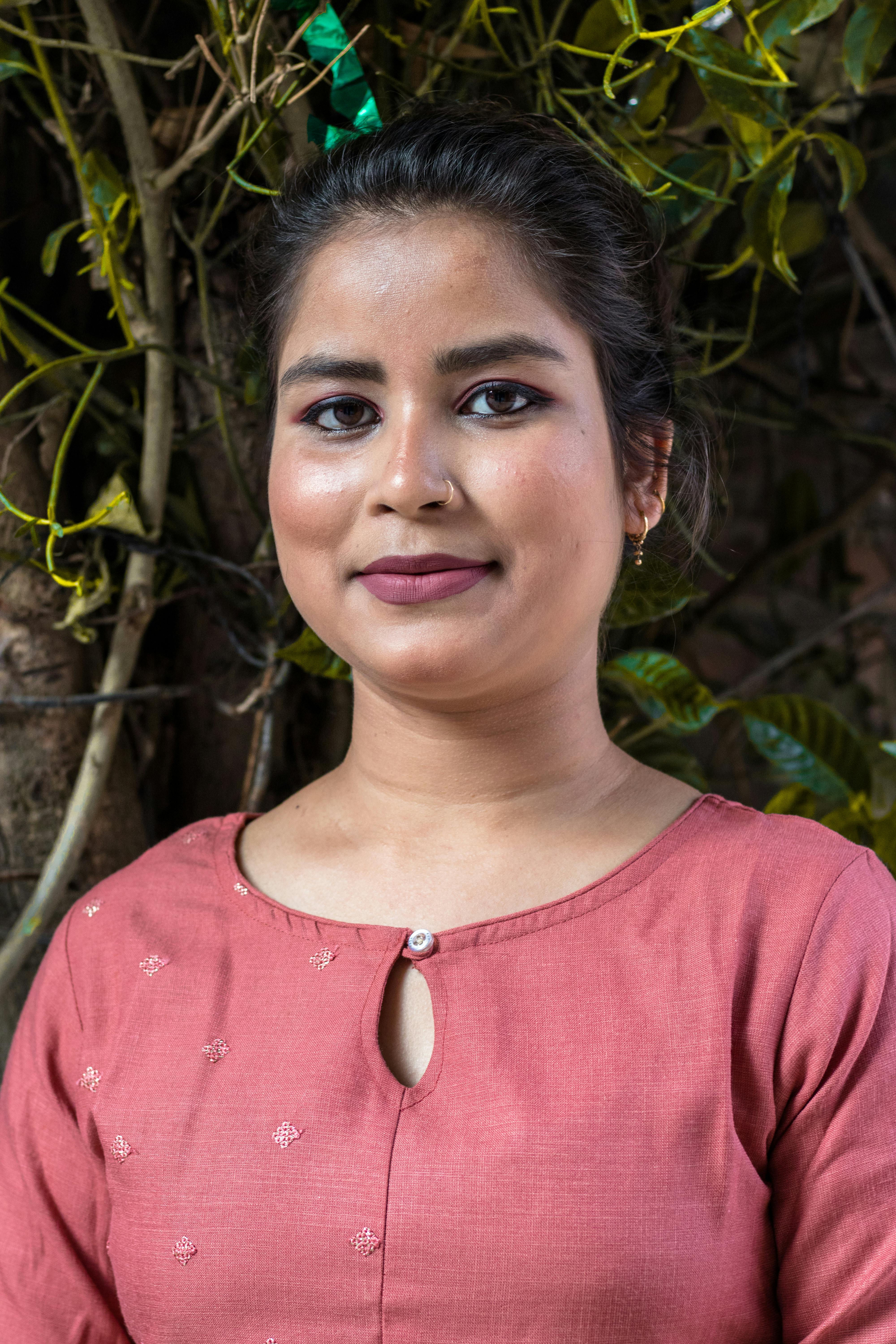 Content ethnic female in casual clothes with makeup looking at camera behind tree