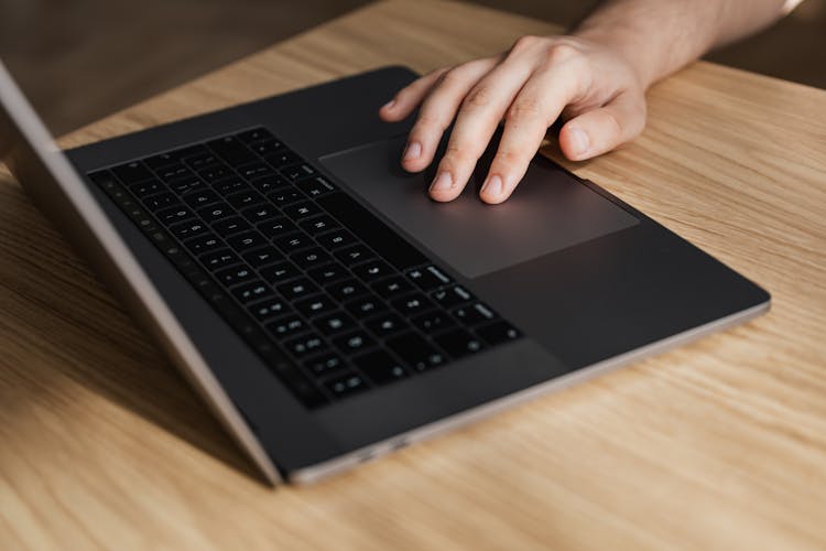 Crop Person Using Touchpad On Laptop