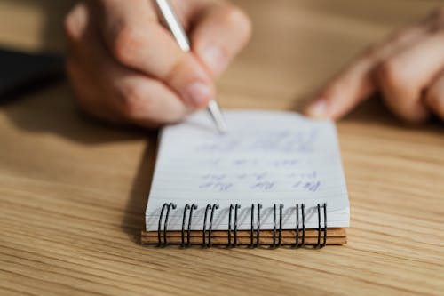Free Crop man writing in notebook with pen Stock Photo