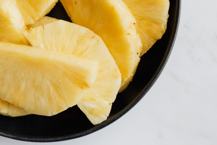 Fresh Pineapple Slices In Black Bowl