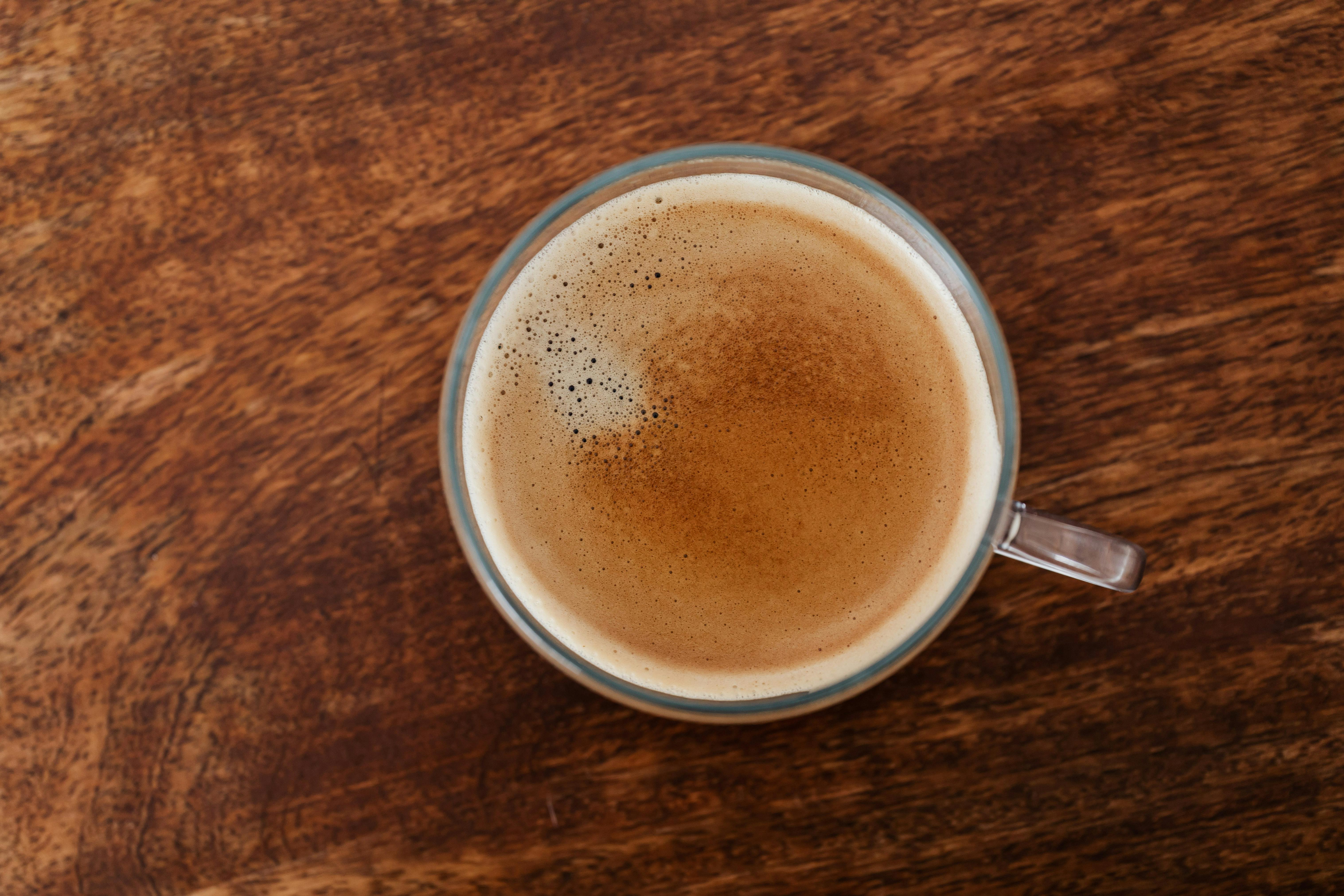 cup of coffee with thin froth on wooden table