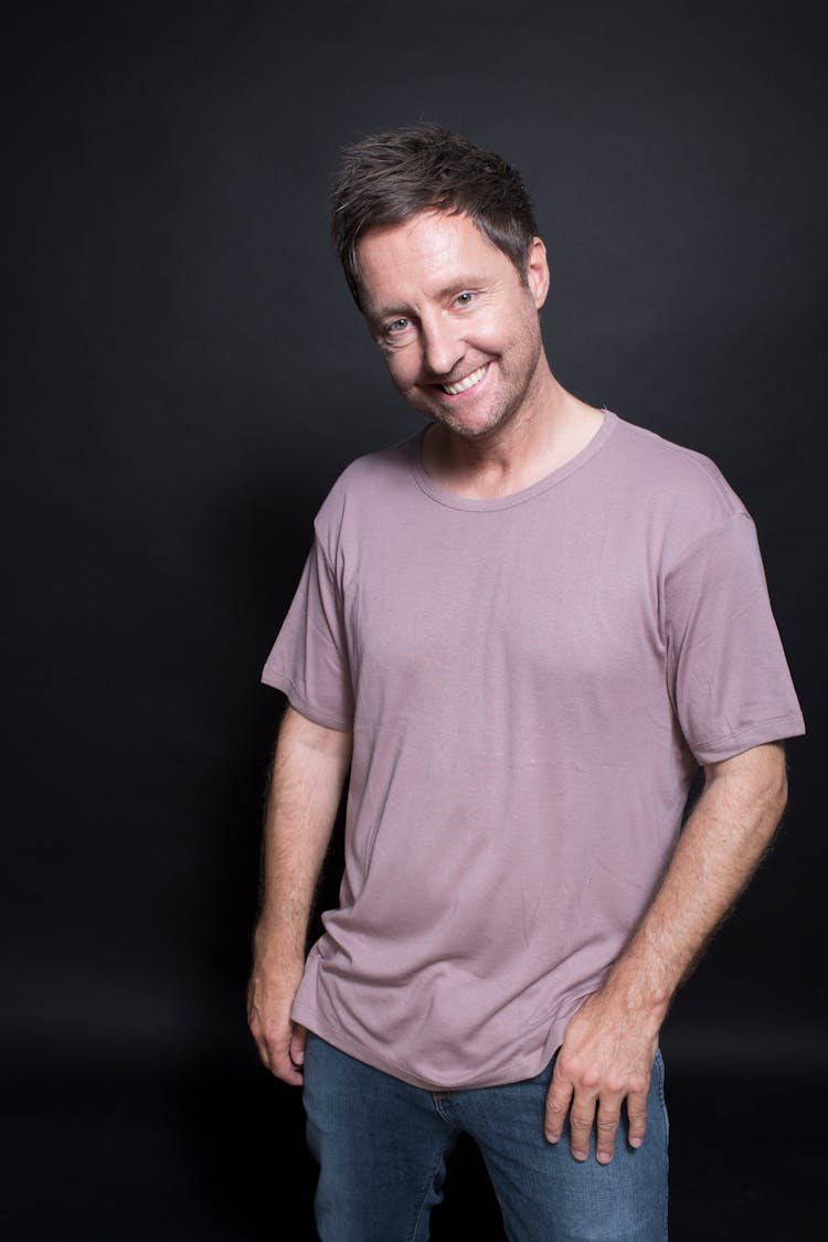 Smiling Mature Man With Tilted Head On Black Background