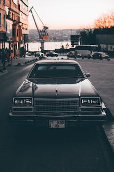 A classic vintage car parked on an İstanbul street at sunset near the Bosphorus.