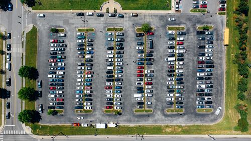 Free Aerial view of parking on asphalt terrain with bright contemporary vehicles near lawns and trees Stock Photo