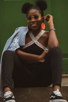 Stylish African woman posing outdoors with vibrant accessories and sunglasses, exuding confidence.