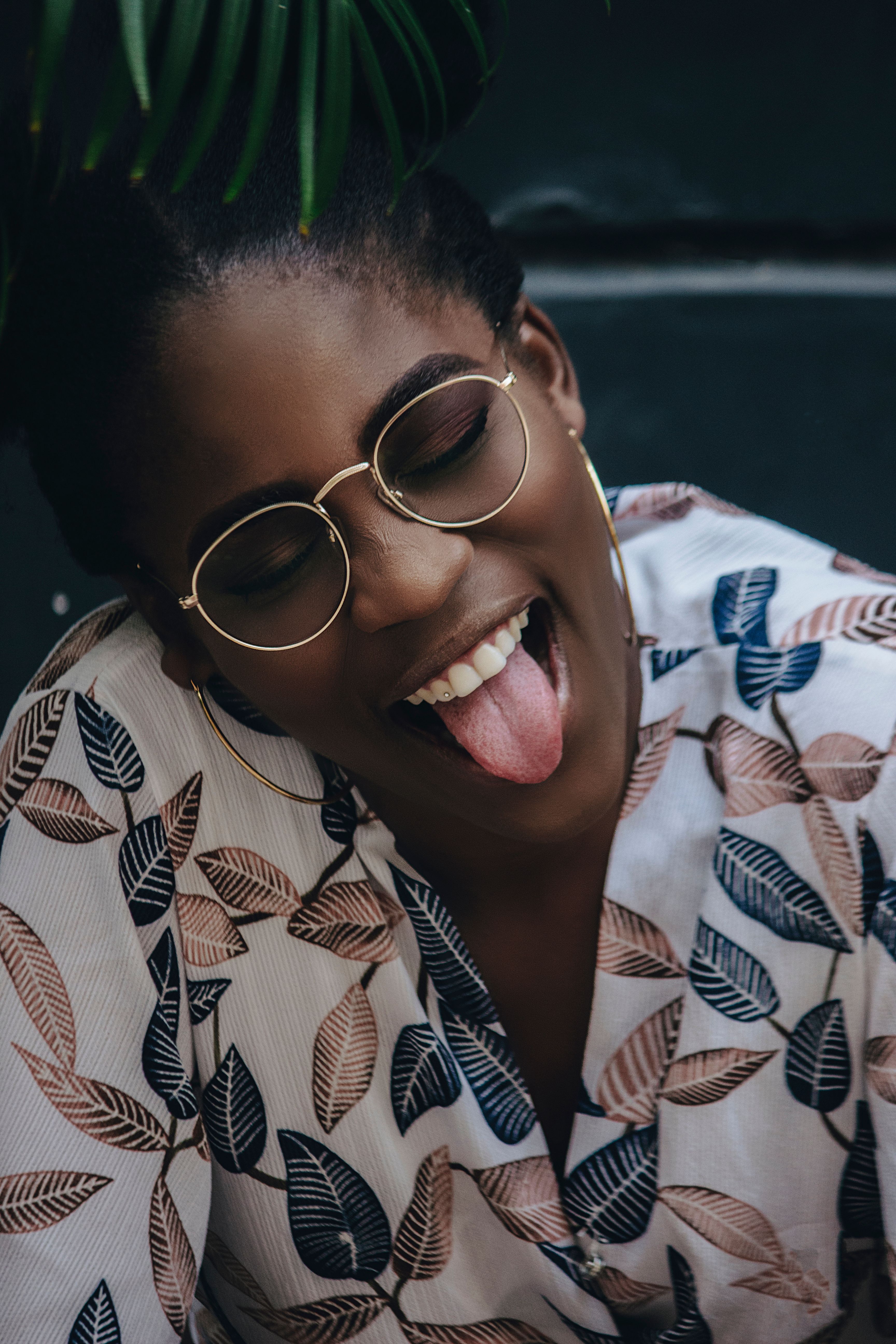 Playful woman in floral shirt displaying humor and happiness outdoors.