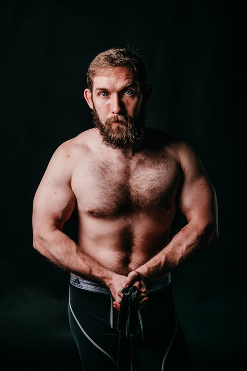 Muscular brutal sportsman with beard on black background