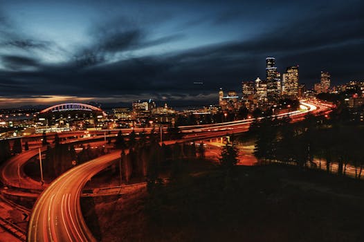 A stunning view of the Seattle skyline at night with vibrant light trails from the highway.