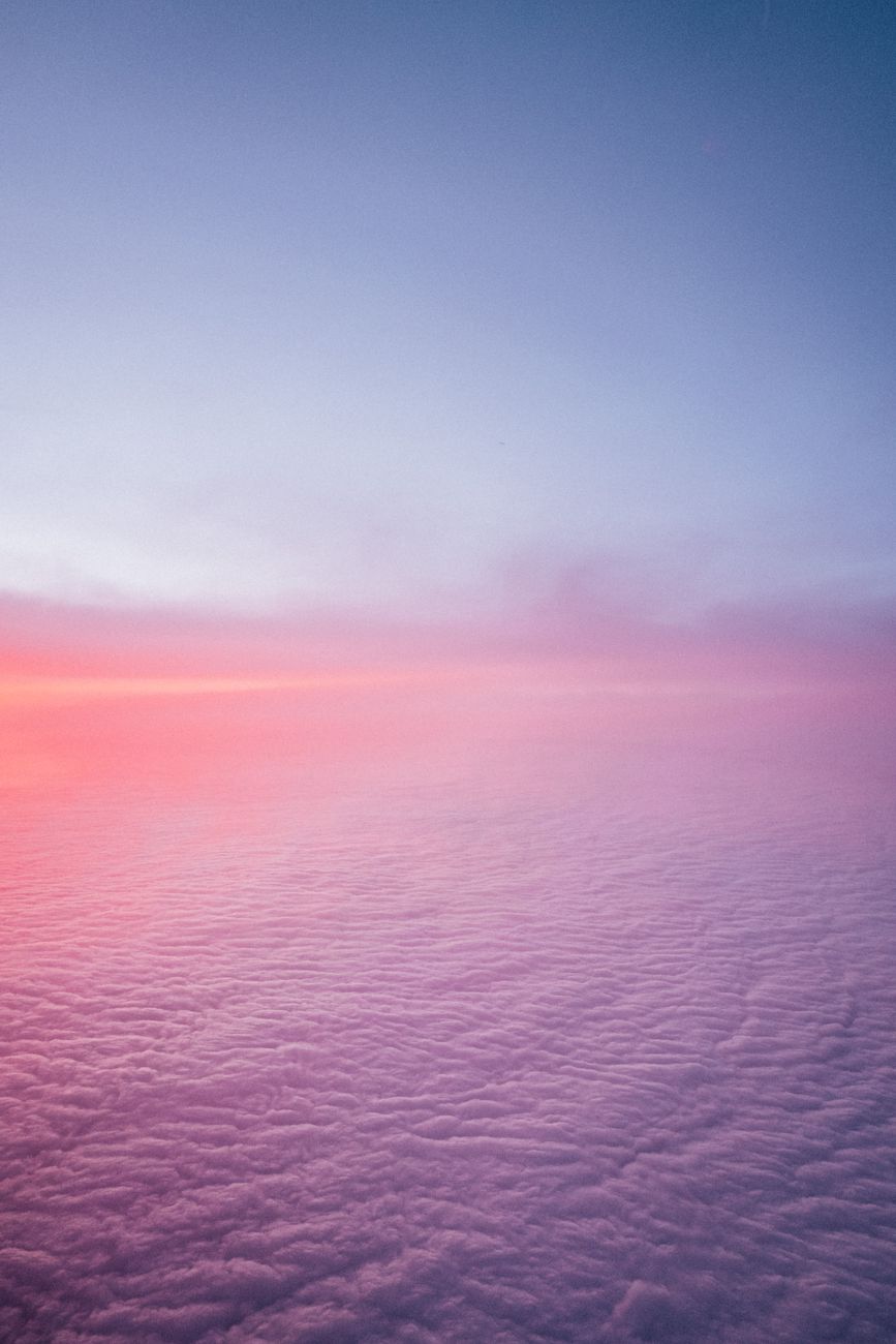 Magical aerial view showcasing a tranquil landscape of pink and blue clouds during sunset, perfect for nature lovers.