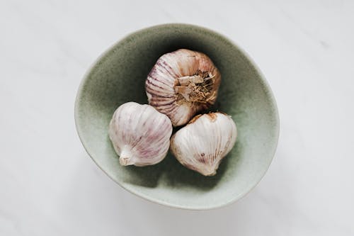 Bowl of garlic bulbs on marble table