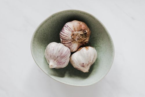 Free Top view of ceramic bowl of garlic heads placed on marble table in soft daylight Stock Photo