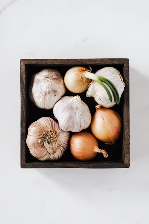 Onions and garlic heads in wooden box on table