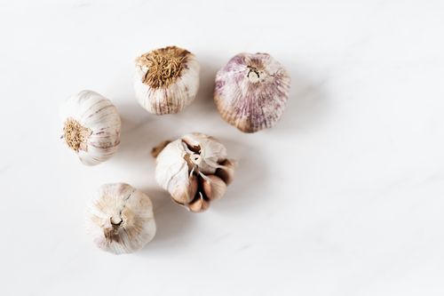 Free Top view of fresh raw organic unpeeled garlic lying close to each other and placed on white marble tabletop under bright light Stock Photo