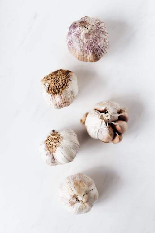 Raw unpeeled garlic on marble surface