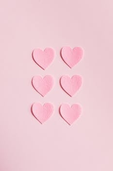 Soft pink heart shapes on a light pink background, perfect for romantic themes.