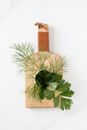 Top view of green sprouts of dill and parsley in cup standing on light brown cutting board on marble table