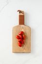 Top view of fresh Datterino tomatoes lying on light brown wooden board on white marble table