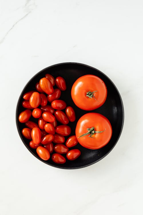 Different sorts of tomatoes in big bowl on table