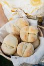 Crop anonymous baker in apron with wicker bowl full of fresh white bread buns