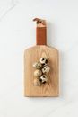 Top view of cutting board with quail eggs lying on white marble table