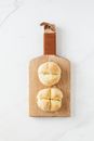 Top view of fresh white bread rolls placed on wooden cutting board lying on marble surface