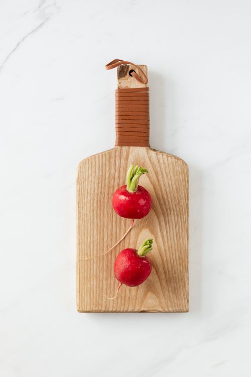 Free Overhead view of fresh clean pink radishes lying on light brown wooden board on white marble table Stock Photo