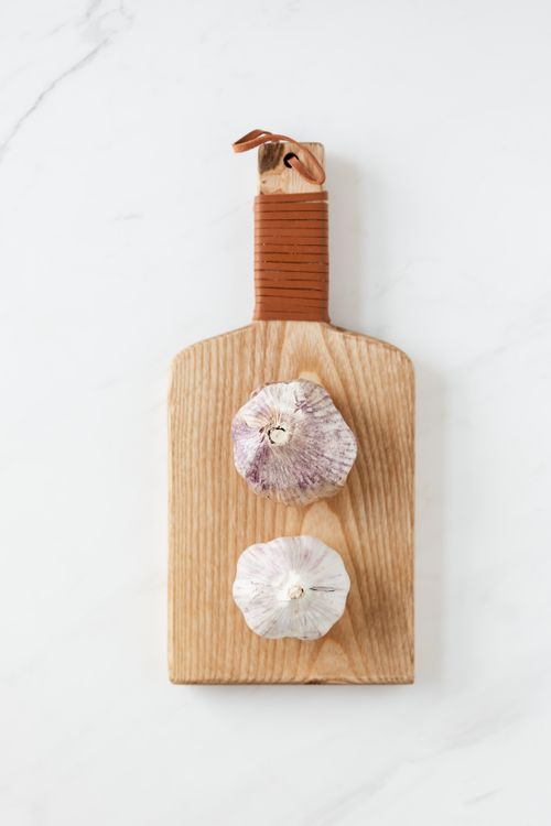 Free Top view of garlic heads placed on wooden kitchen board on white marble table Stock Photo