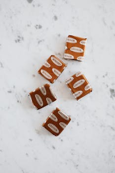 Overhead view of stock cubes in brown wrappers lying on marble kitchen table by Photo By: Kaboompics.com