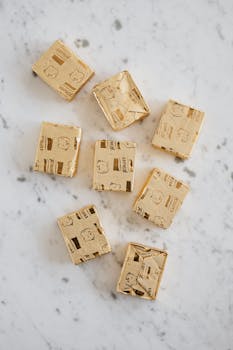 Overhead view of broth cubes in shiny golden package lying on white marble table