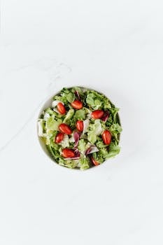 Top view of a fresh and healthy green salad with ripe grape tomatoes in a bowl.