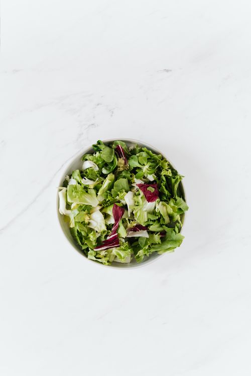 Free Top view of bowl with salad made of fresh lettuce and red cabbage on white marble table Stock Photo