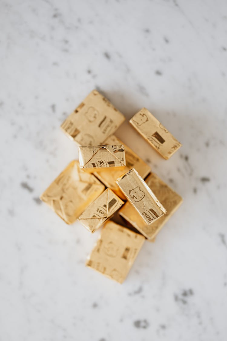 Broth Cubes In Golden Wrappers On Table