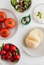 Top view of fresh vegetables and vitamin salad together with quail eggs and cottage cheese complemented with wheat bread on plates and in bowls on marble table