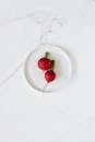 Top view of fresh red radishes placed in ceramic bowl standing on white marble table