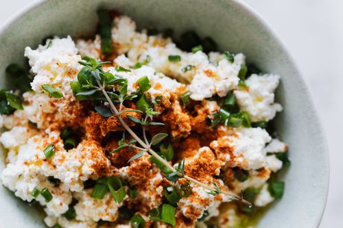 Free Top view of bowl with healthy salad with cottage cheese green onion and brunch of thyme placed on table in kitchen Stock Photo
