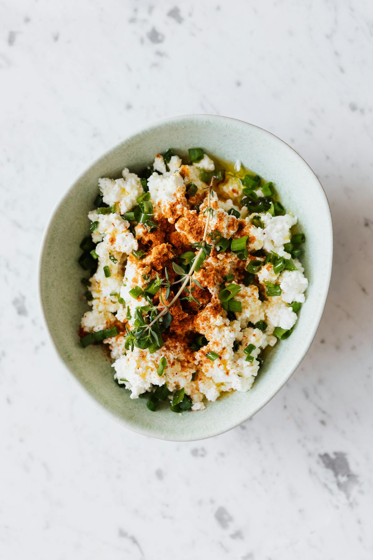 Ciotola vista dall'alto con ricotta e erbe fresche intorno
