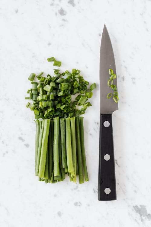 Fresh green onion and knife on white table