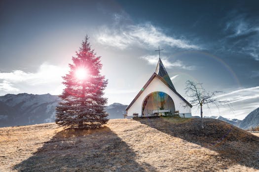 在戏剧性的天空下，教堂与日出被周围的山脉和树木环绕