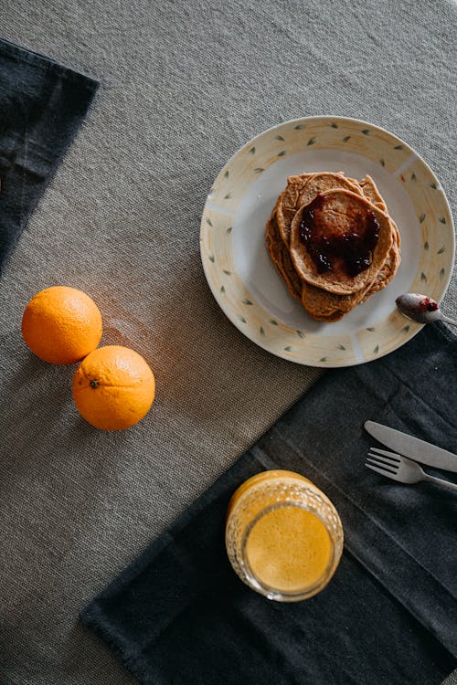 Orange Fruits beside a Plate of Pancakes