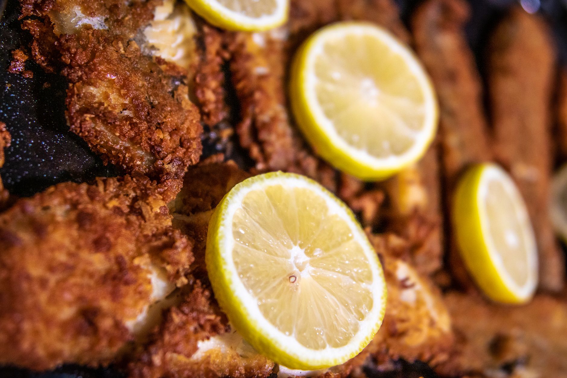 Golden fried sand dab fillets garnished with parsley and lemon wedges