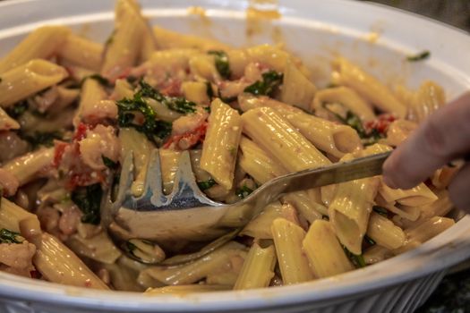 Close-up of a savory pasta dish with creamy sauce, vegetables, and fresh ingredients.