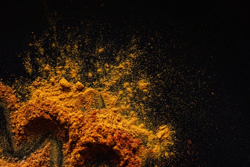 Composition of multicolored ground spices spilled on black background
