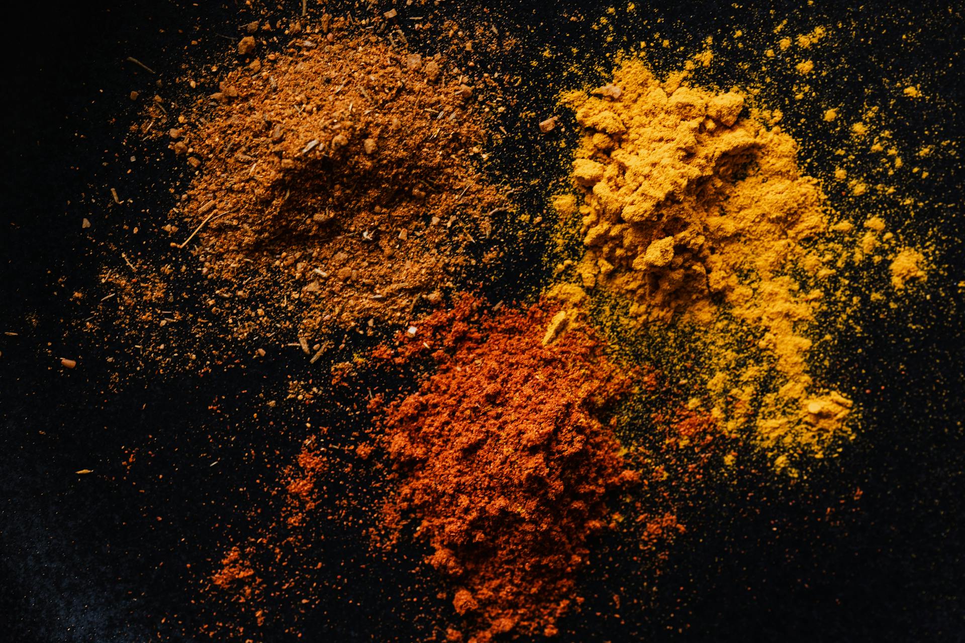 Assorted colorful dry powdered spices on black background