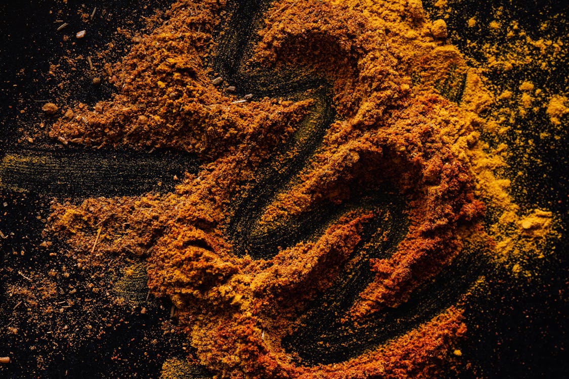 From above of creative design of smoked ground paprika and turmeric mixed together on black surface