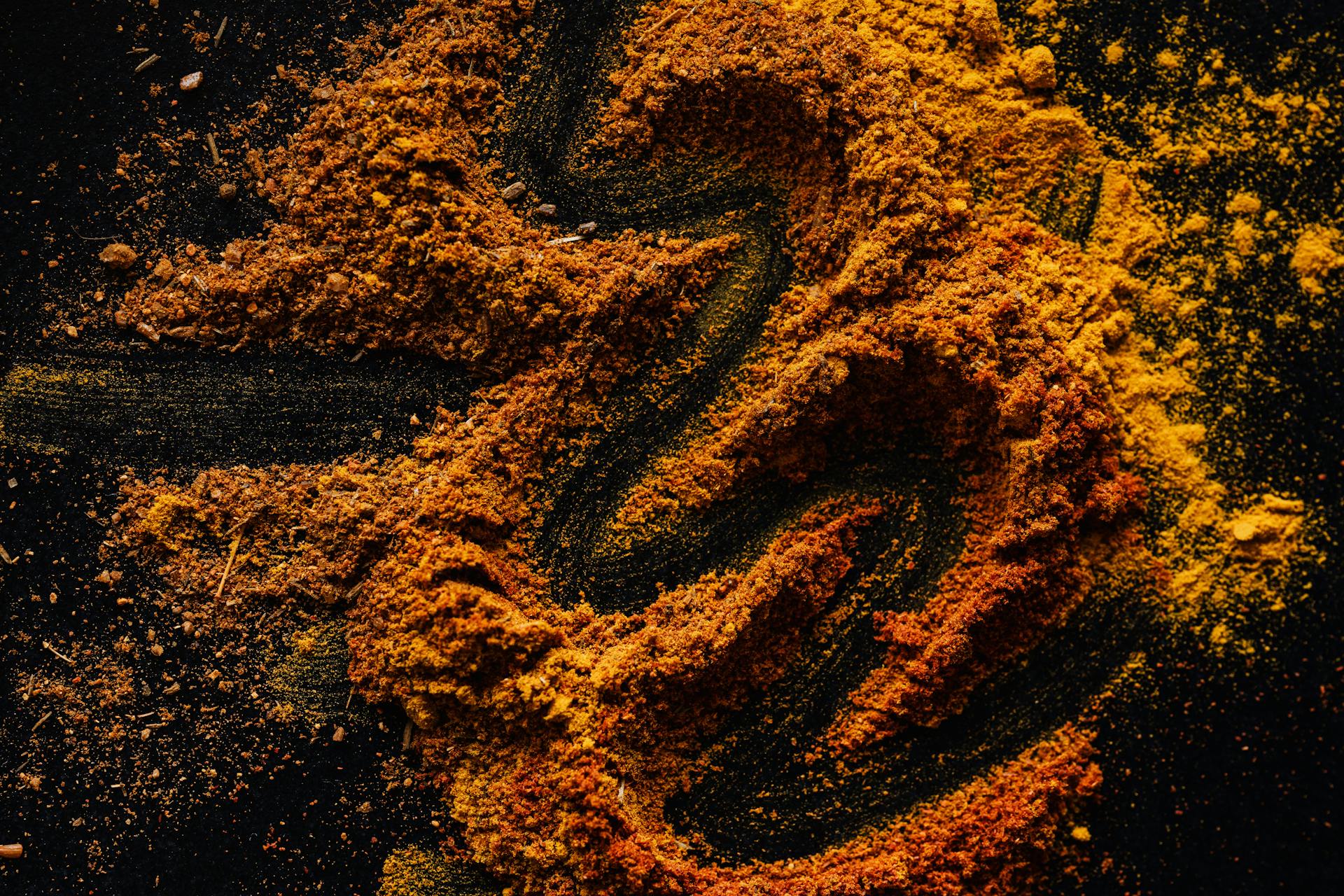 From above of creative design of smoked ground paprika and turmeric mixed together on black surface