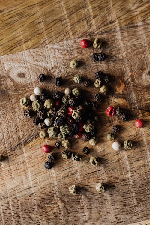 Top view of pile of round dried assorted pepper seeds with dense texture spilled on wooden table