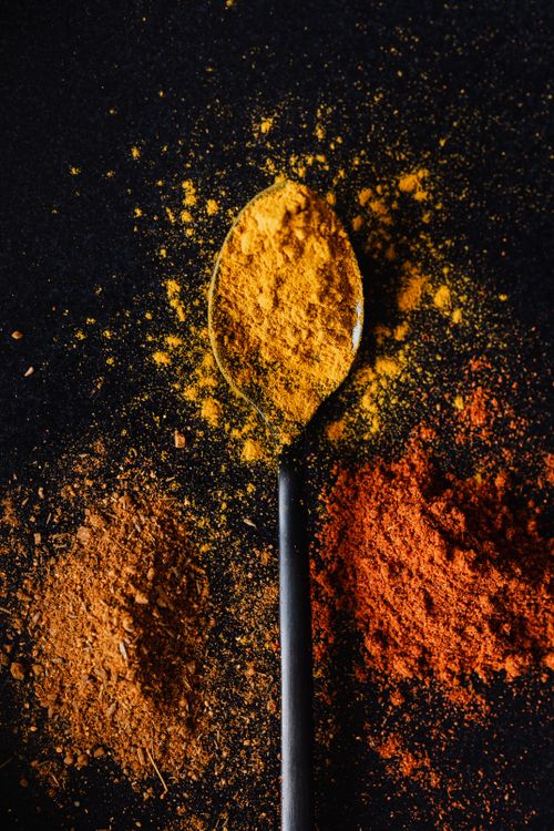 Free Top view of heap of powdered paprika and mix of peppers with bright curcuma in center on tablespoon on black background Stock Photo